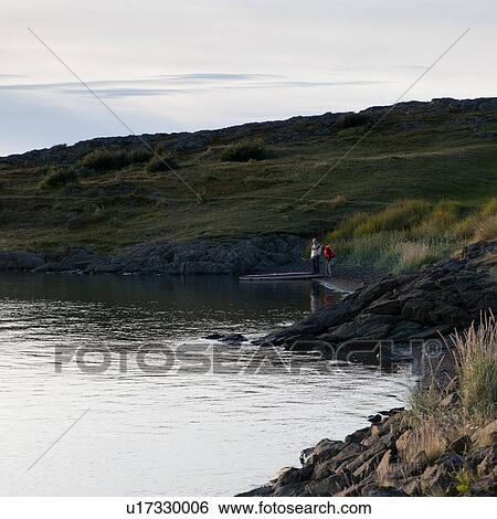 Stock Photograph - Rocky ocean shoreline, with sightseers and boat. Fotosearch