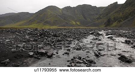 Stock Photography - Rocky river bed below rugged mountains. Fotosearch