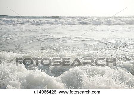 Stock Photograph - rolling ocean waves parallel to the horizon on an overcast day. Fotosearch
