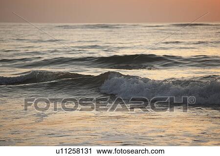 Stock Image - Rolling waves on the ocean in the evening glow. Fotosearch