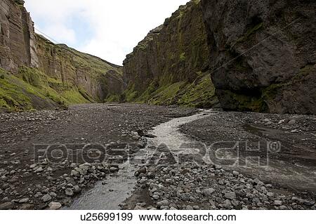 Stock Photo - Rugged mountain canyon landscape with rocky riverbed and stream. Fotosearch
