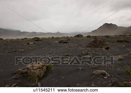 Stock Image - Rugged mountain landscape with dry riverbed and dust rising. Fotosearch