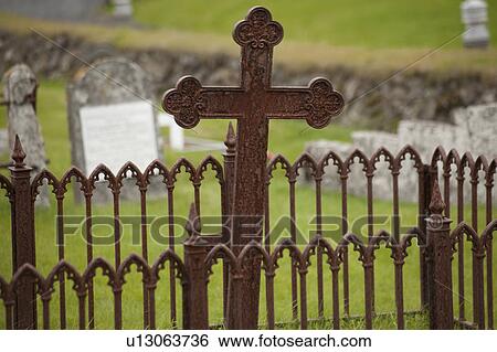 Stock Photograph - Rusted gate and cross in graveyard. Fotosearch