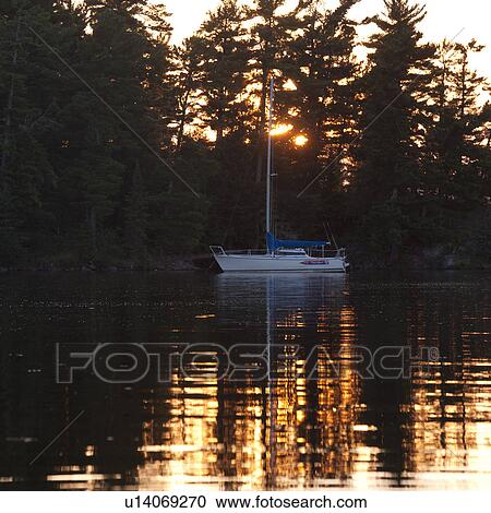 Sailboat anchored on lake at sunset in Lake of the Woods, Ontario View Large Photo Image Stock Image - Sailboat anchored on lake at sunset in Lake of the Woods, Ontario. Fotosearch