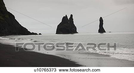 Stock Image - Sandy beach, rugged cliffs at the ocean. Fotosearch