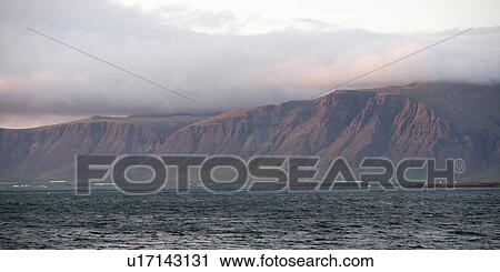 Stock Image - Seascape, ocean and cloud topped cliffs in evening. Fotosearch