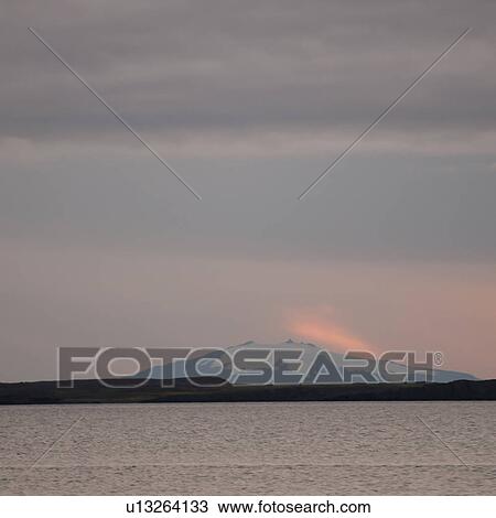 Stock Image - Seascape, snowy mountain in the rosy evening sunset. Fotosearch