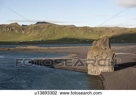 Stock Image - Seashore along black sand beach with cliff eroding into scree. Fotosearch