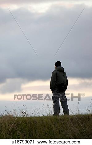 Silhouette person standing on hilltop cloudy evening View Large Photo Image Stock Image - Silhouette person standing on hilltop cloudy evening. Fotosearch