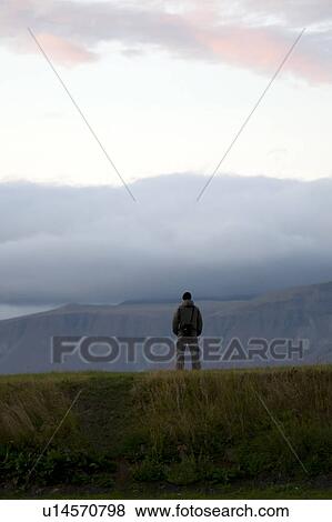 Stock Photo - Silhouette person standing on hilltop cloudy evening. Fotosearch