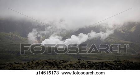 Stock Image - Smoke rising from valleys into clouded mountains. Fotosearch