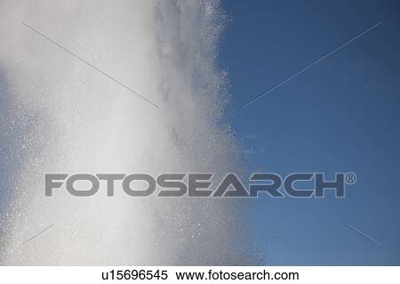 Stock Photography - Spray of geyser steam in the blue sky. Fotosearch