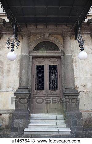 Stock Image - Steps leading to canopied double entrance doors flanked by marble columns and matching hanging exterior light fixtures. Fotosearch