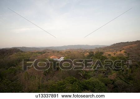Sun fading over a white house with an orange roof in the rolling hills above the treetops of Costa Rica View Large Photo Image Stock Image - Sun fading over a white house with an orange roof in the rolling hills above the treetops of Costa Rica. Fotosearch