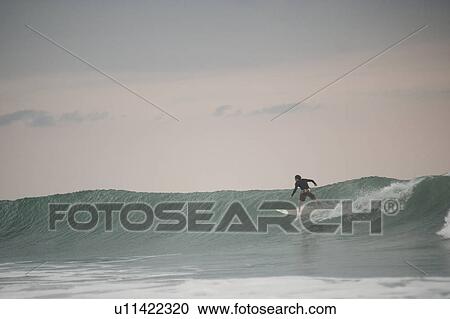Stock Image - Surfer along Mal Pais coastline in San Jose Costa Rica. Fotosearch