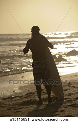 Stock Image - Surfer along Mal Pais coastline in San Jose Costa Rica. Fotosearch