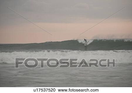 Stock Image - Surfer along Mal Pais coastline in San Jose Costa Rica. Fotosearch