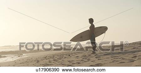 Stock Image - Surfer along Mal Pais coastline in San Jose Costa Rica. Fotosearch
