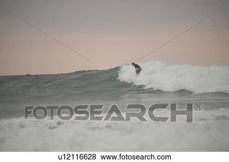 Stock Photo - Surfer along Mal Pais coastline in San Jose Costa Rica. Fotosearch