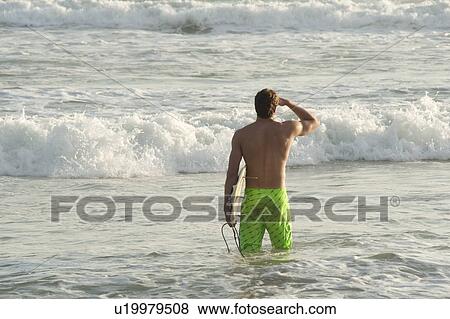 Stock Photo - Surfer along Mal Pais coastline in San Jose Costa Rica. Fotosearch