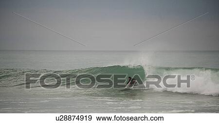 Stock Photo - Surfer along Mal Pais coastline in San Jose Costa Rica. Fotosearch