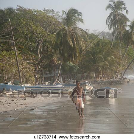 Surfer along ocean seashore in Costa Rica View Large Photo Image Picture - Surfer along ocean seashore in Costa Rica. Fotosearch