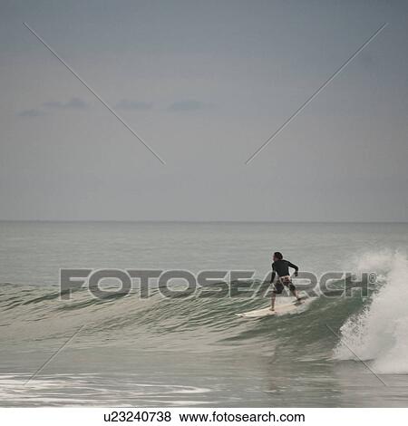 Stock Photo - Surfer riging a wave along Coast Rica seashore. Fotosearch