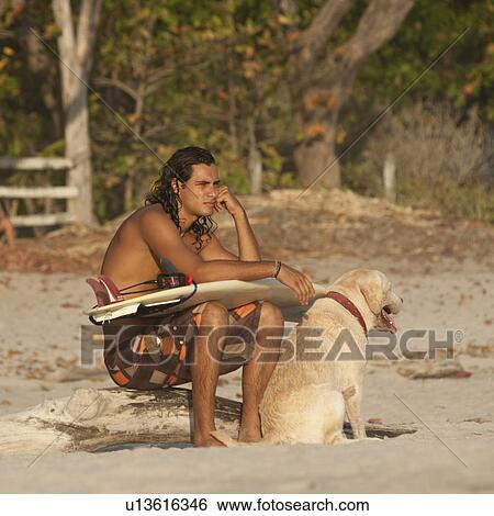 Stock Photograph - Surfer with his dog along Costa Rica beach. Fotosearch