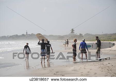 Stock Photo - Surfers on the shore of Nosara on a hazy day. Fotosearch