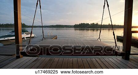Stock Photography - Suspended lounge chair on the dock in Lake of the Woods, Ontario. Fotosearch