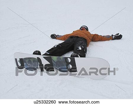 Stock Image - Teenage girl laying in the snow on a ski slop in Vail, Colorado. Fotosearch