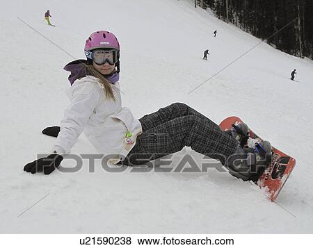 Stock Photo - Teenage girl sitting on a ski hill with a snow boad in Vail, Colorado. Fotosearch