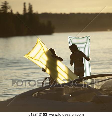 Stock Image - Two girls with float mattresses at Lake of the Woods, Ontario. Fotosearch