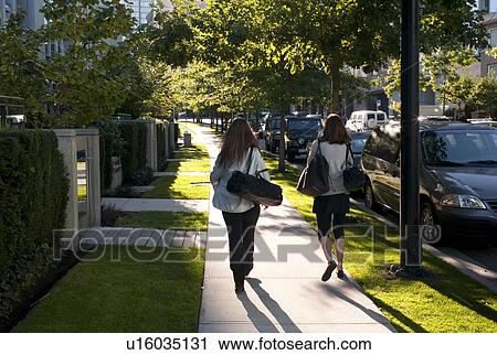 Stock Image - Two women walking on a sidewalk in Vancouver, British Columbia, Canada. Fotosearch
