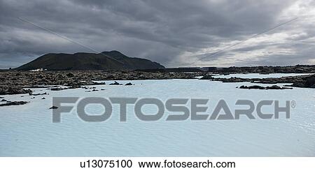 Stock Image - Volcanic geothermal lagoon, rugged landscape, stormy sky. Fotosearch