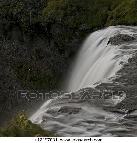 Stock Image - Waterfall cascade in verdant grassland. Fotosearch