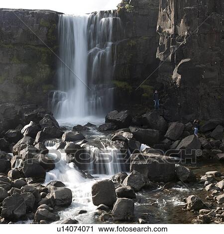 Stock Image - Waterfall over cliff onto boulders. Fotosearch