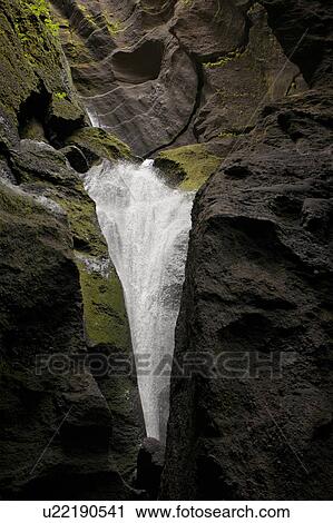 Stock Image - Waterfall over rocky cliffs in Iceland. Fotosearch