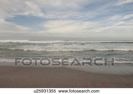 Waves breaking on the beach under a cloudy blue sky View Large Photo Image Stock Photography - Waves breaking on the beach under a cloudy blue sky. Fotosearch