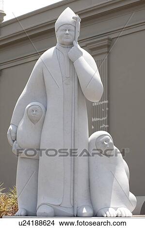 Picture - White marble statue of a priest sheltering two children. Fotosearch