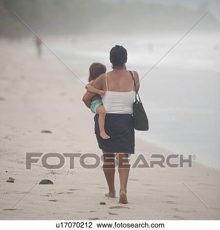 Woman carrying a child on the shoreline in Costa Rica View Large Photo Image Stock Image - Woman carrying a child on the shoreline in Costa Rica. Fotosearch
