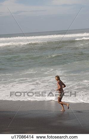 Woman in bathing suit jogging along the beach besides the waves View Large Photo Image Picture - Woman in bathing suit jogging along the beach besides the waves . Fotosearch
