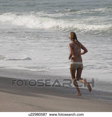 Stock Photo - Woman jogging on the beach in Costa Rica. Fotosearch