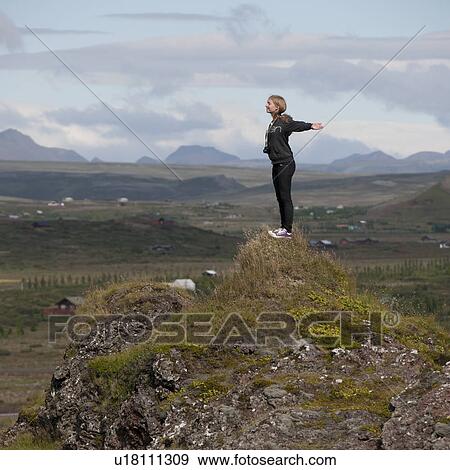 Woman stretching on rocky hill outcrop above farmland before mountains View Large Photo Image Stock Photo - Woman stretching on rocky hill outcrop above farmland before mountains. Fotosearch
