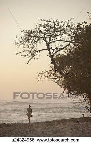 Stock Photograph - Woman walking along Mal Pais coastline in San Jose Costa Rica. Fotosearch