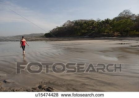 Stock Photo - Woman walking on the beach, San Jose Costa Rica. Fotosearch