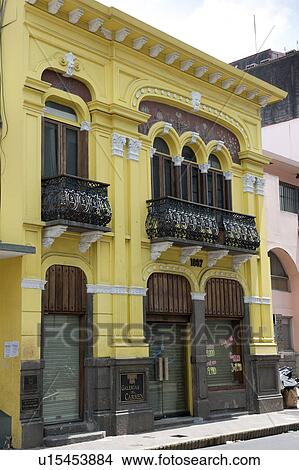 Picture - Yellow two storey building with wrought iron balcony and arched windows with columns and keystones. Fotosearch