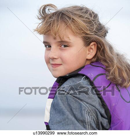 Stock Photo - Young blond girl looking over her shoulder at the camera at Lake of the Woods, Ontario. Fotosearch