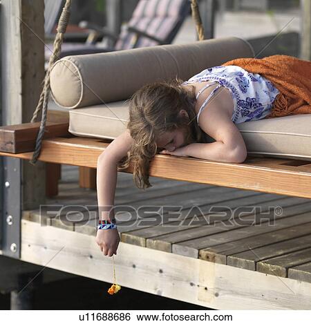 Stock Photograph - Young girl relaxing on a lounge chair at Lake of the Woods, Ontario. Fotosearch