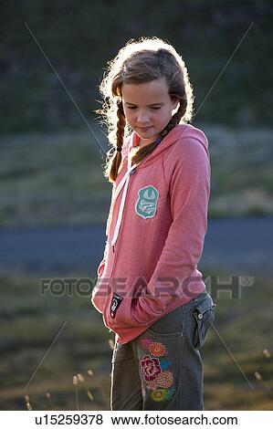 Young girl standing alone in a field in Iceland View Large Photo Image Stock Photo - Young girl standing alone in a field in Iceland. Fotosearch